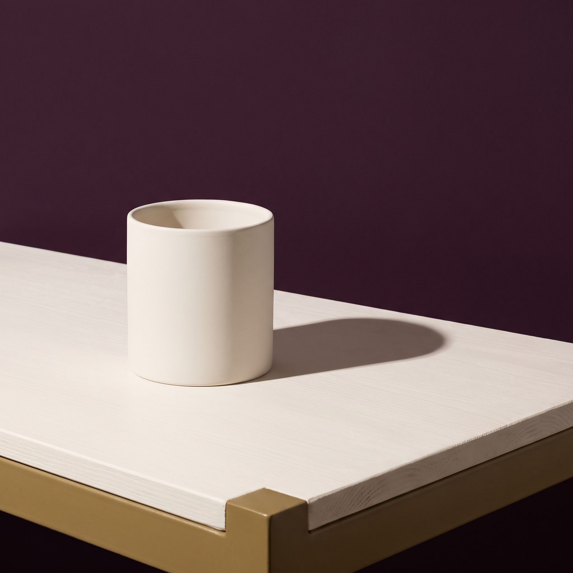 An empty pale workbench with one plain white container at the left, against a plum wall.