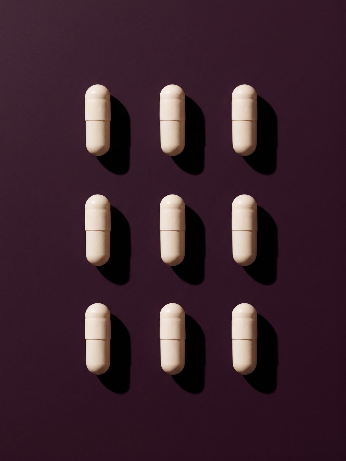 Nine plain white capsules in a three by three grid.