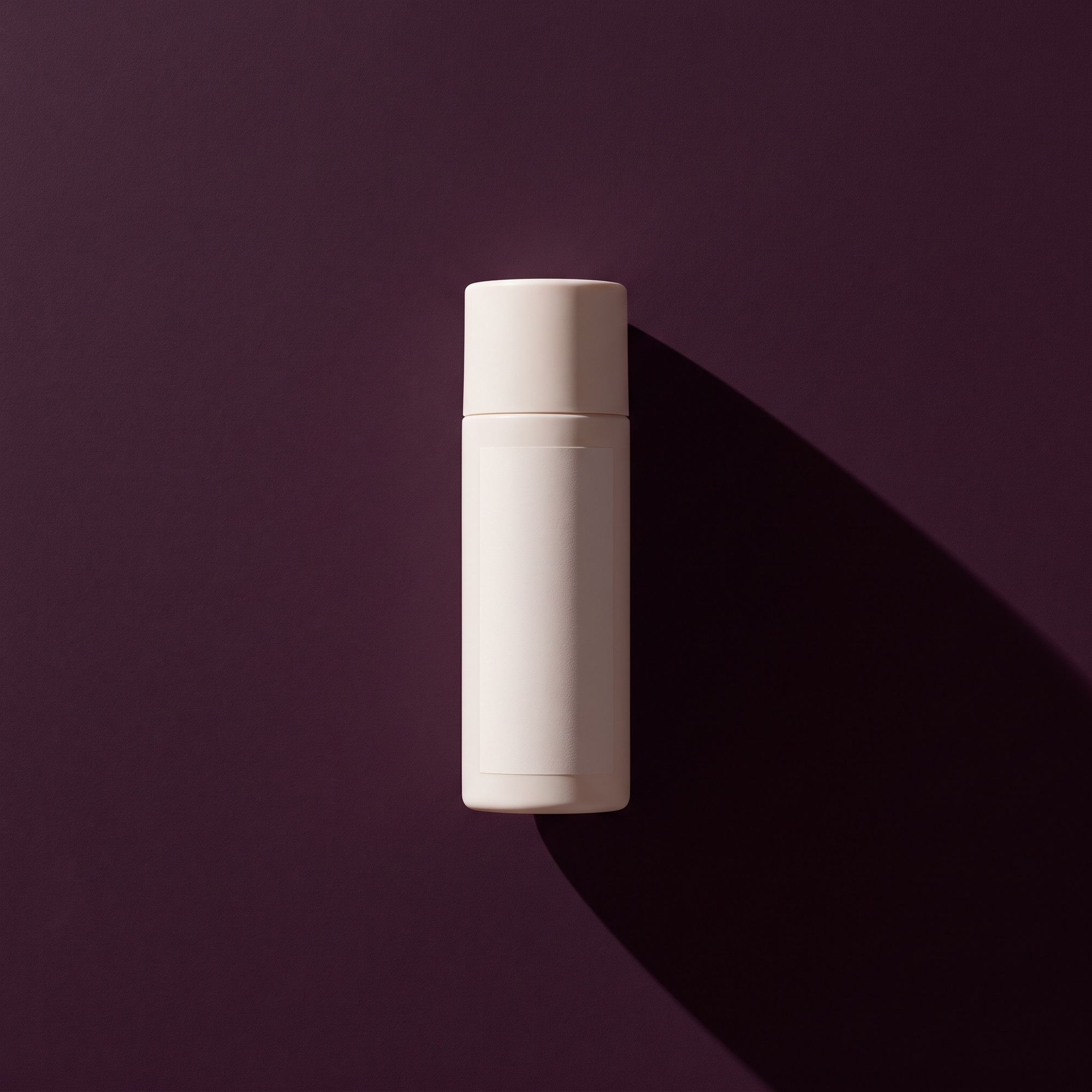 A plain white bottle on a deep plum surface under one hard light.
