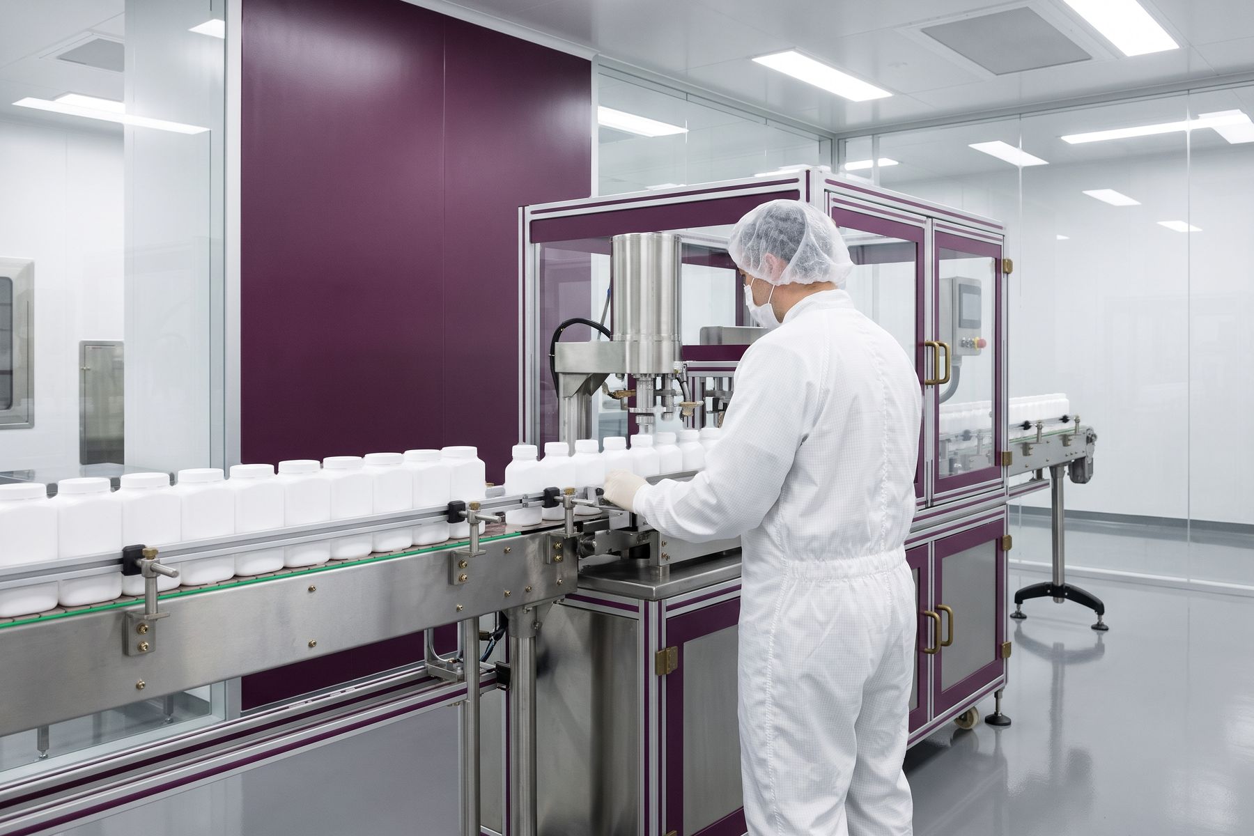 A production line filling and capping plain unlabelled white containers.