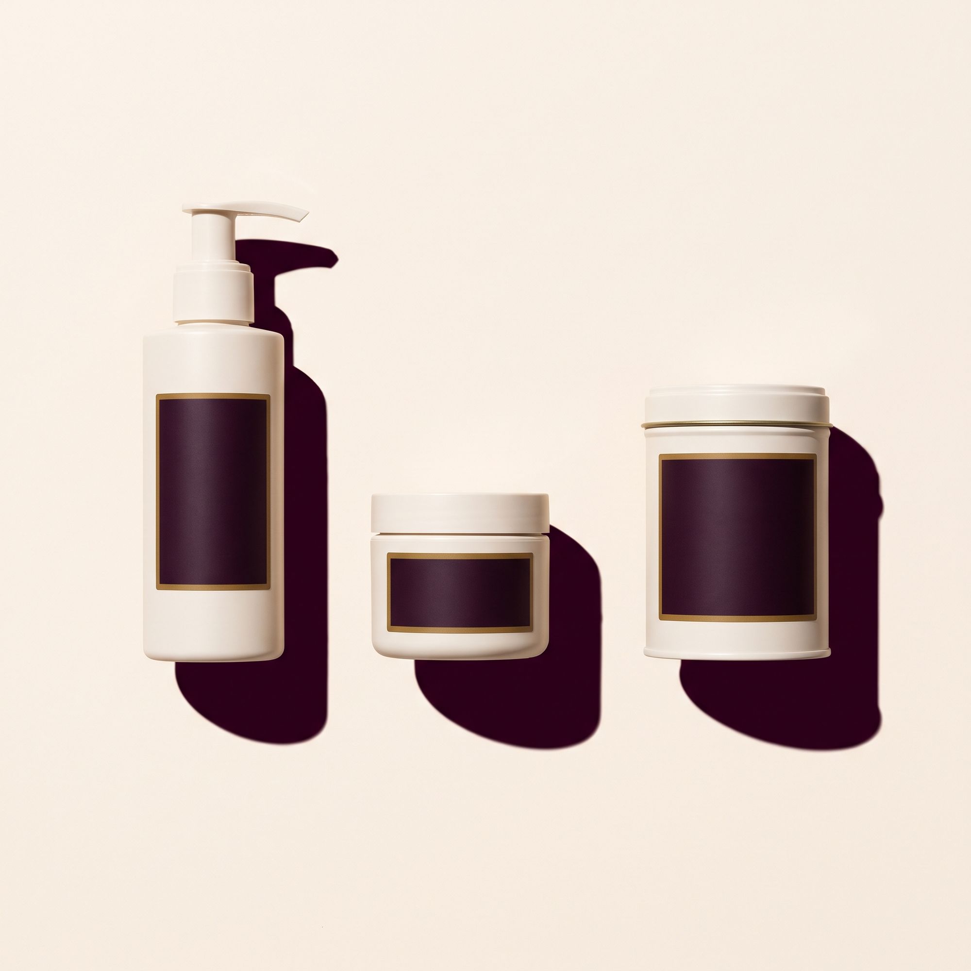 Three white containers in a row on a paper coloured surface, each carrying a blank plum label panel.